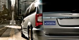 Minivan on a city street with a bumper sticker reading "IIHS Top Safety Pick."