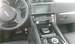 Interior de un coche de lujo con volante y pantalla central en el panel de control.