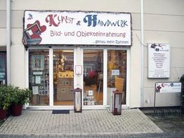 Geschäft "Kunst & Handwerk" mit Schaufenster und Schildern für Einrahmungen.