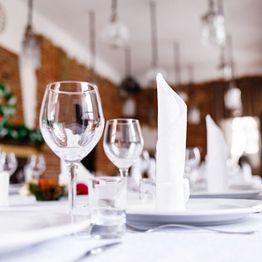 Elegant table setup with glassware and napkins in a softly lit dining room.