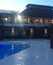 Edificio moderno al atardecer con piscina iluminada en primer plano.