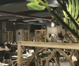 Elegantes Restaurant mit Holzdeko, gedeckte Tische, gemütliches Ambiente.