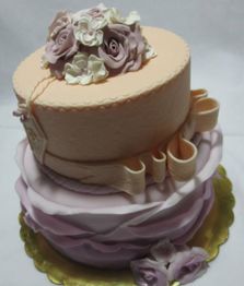 Torta a due piani decorata con fiori di zucchero rosa e crema su un vassoio dorato.