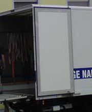 Umzugs-LKW vor einem Gebäude, Möbel werden mit einer Außenleiter in obere Etagen transportiert.