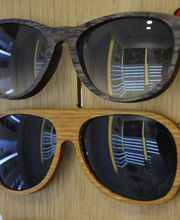 Dos gafas de sol de madera en un soporte, con reflejos visibles en las lentes.