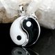 Yin-Yang-Anhänger aus schwarzem und weißem Material, liegend auf einem Kristallhintergrund.