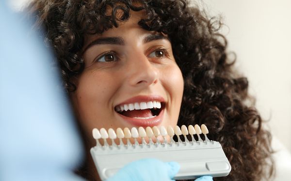Zahnarzt prüft die richtige Zahnfarbe der Patientin für ihre Veneers.