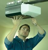 Man installing a garage door opener on the ceiling.