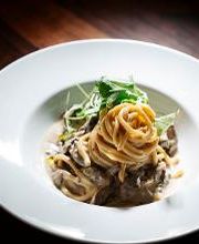 Prato com macarrão ao molho cremoso e ervas, em um fundo de madeira escura.