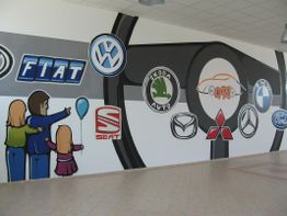 Wand mit bunten Auto-Logos und Figuren: Fiat, VW, Škoda, Seat, Mazda, Mitsubishi, BMW, Ford.