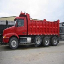 A red dump truck parked outdoors on a cloudy day.