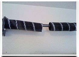 Dual black metal torsion springs on a rod, mounted on a white background.