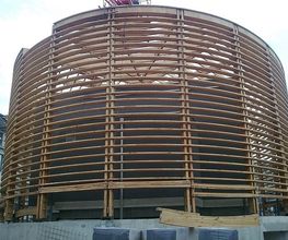 Runde Holzkonstruktion mit Lattengerüst auf Baustelle, unfertiger Zustand.