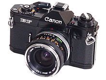 A vintage Canon camera with a lens cap attached, shown at an angle.