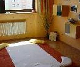 Ein einfaches Schlafzimmer mit Matratze am Boden und Fenster mit Blick auf Gebäude.