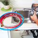Person fixing a kitchen sink with red and blue hoses nearby.