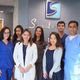 Group of medical professionals posing in a clinic lobby with a logo in the background.