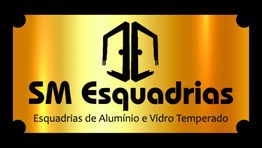 Placa dourada com texto: "SM Esquadrias, Esquadrias de Alumínio e Vidro Temperado" em preto.