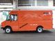 Orange Foodtruck mit Aufschriften wie "Berlin", "Bratislava", "Eiscreme", "Hot Dog" in einer Halle.