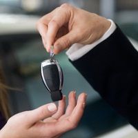 Person handing over car keys to another person.