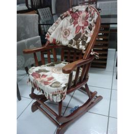 Cadeira de balanço de madeira com almofadas estampadas em floral colorido, em exposição.