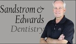 Man smiling with folded arms beside Sandstrom & Edwards Dentistry sign.