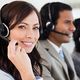 Woman in headset smiling, working in a call center with colleagues.