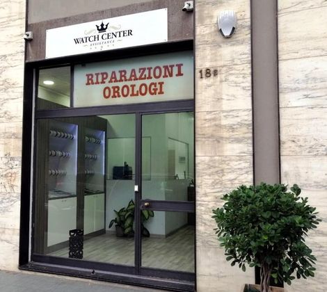 Facciata di un negozio di riparazione orologi con porta in vetro e insegna "WATCH CENTER".