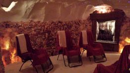 Salzraum mit Liegestühlen, Salzsteinwänden und einem Wasserfall, sanft beleuchtet für Entspannung.