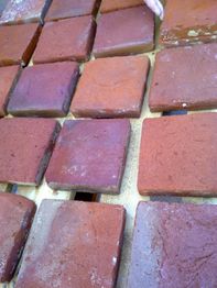 Rote Ziegelsteine, die auf Holzpaletten angeordnet sind.