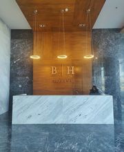 Recepción moderna con mostrador de mármol en una oficina con luces colgantes y una persona.