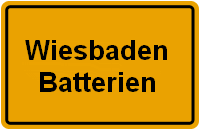 Ortsschild mit der Aufschrift "Wiesbaden Batterien" in Schwarz auf gelbem Hintergrund.