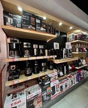 Estantería de tienda con cafeteras y cajas de diferentes marcas expuestas para la venta.