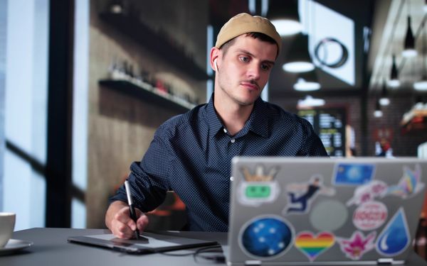 Ein Freelancer sitzt in einem Cafe und arbeitet an einem Projekt eines Kunden.