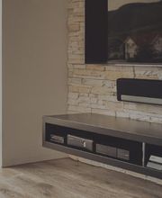 Wohnzimmer mit Wandregal, Fernseher und moderner Medienkonsole auf Parkettboden.