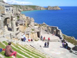 Steinernes Amphitheater am Meer mit Besuchern und steinernen Strukturen, umgeben von Felsen.