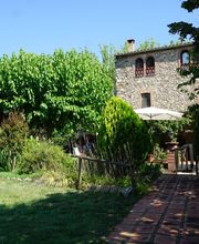 Casa de piedra con jardín, vegetación abundante y camino de ladrillo bajo un cielo despejado.