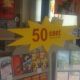 Ein gelbes Schild in Sternform mit rotem Text: "50 cent" über DVDs in einem Laden.