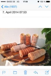 Verschiedene Baumstriezel auf einem Holzbrett, teils mit Zucker oder Nüssen bestreut.