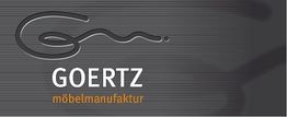 Logo von Goertz Möbelmanufaktur mit geschwungenem, abstraktem Design auf grauem Hintergrund.