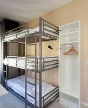 Schlafzimmer mit Etagenbett, offenem Kleiderschrank, Tisch und hellem Fenster.