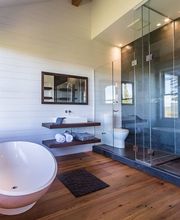 Modernes Badezimmer mit freistehender Badewanne, großer Dusche und Holzfußboden.