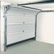 White sectional garage door partially open in a light grey garage space.