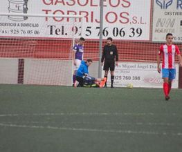 Jugadores de fútbol en campo, uno lesionado. Anuncios de empresas locales al fondo.