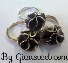 Quattro anelli con montatura floreale in metallo, disposti in cerchio.