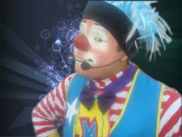 Payaso con disfraz colorido y micrófono en fondo oscuro con efectos circulares.