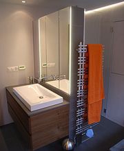 Modernes Badezimmer mit Waschbecken, Spiegel und Handtuchhalter mit orangefarbenem Handtuch.