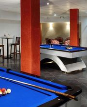 Sala de juegos con mesa de billar, futbolín, diana, air hockey y sillas altas.