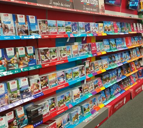 Scaffale con guide turistiche colorate in libreria.