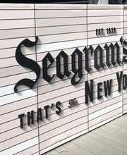 Cartel publicitario de Seagram's Gin y Bagel en un espacio urbano.